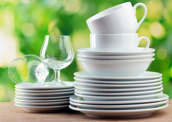 Clean dishes on wooden table on green background