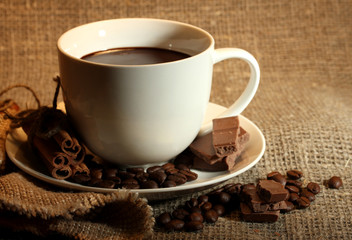 cup of coffee, beans and chocolate on sacking background