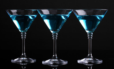 Blue cocktail in martini glasses isolated on black