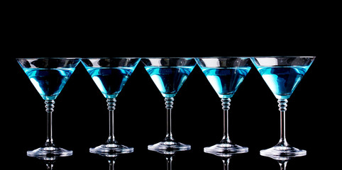 Blue cocktail in martini glasses isolated on black