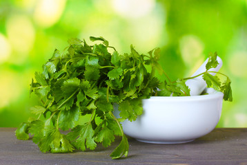 Coriander in a mortar and pestle on green background