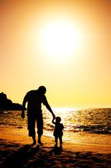 father and daughter playing on the beach at sunset