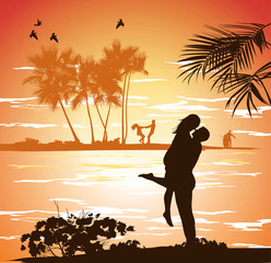 man embraces woman on the shore of the beach at sunset