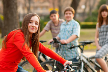 Beautiful teenage girl with her friends riding bicycles