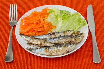 fried sardines with lettuce and carrot on the plate