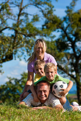 Familie mit Kindern und Fußball auf einer Wiese