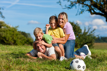Familie mit Kindern und Fußball auf einer Wiese