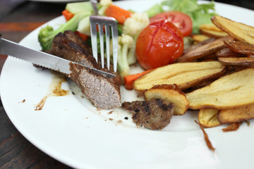 Grilled steak with vegetables on wood background