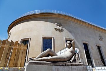 Statue de femme allongée et palissade en bois.