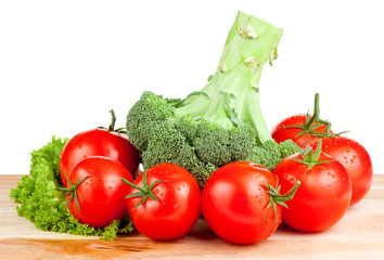 Fresh wet tomatoes, brocolli and lettuce on a cutting board wood