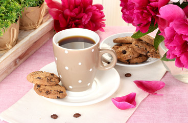 cup of coffee, cookies and flowers on table in cafe