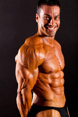 male bodybuilder flexing muscle on black background