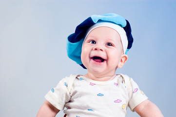Amusing baby boy in a beret in a studio on a dark blue backgroun