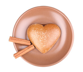Fototapeta na wymiar Heart-shaped cookie with cinnamon on saucer isolated on white
