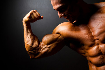 strong bodybuilder posing on black background