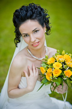 portrait of beautiful young bride in garden with bouquet