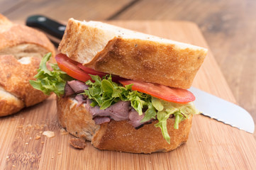 Fresh roast beef sandwich on wood cutting board.