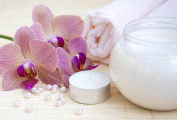 Fototapeta na wymiar cosmetic cream with pink orchids and towel