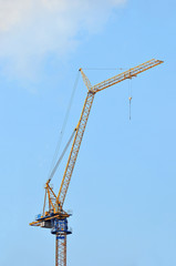 Naklejka premium Yellow construction tower crane against blue sky