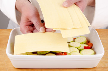 female chef fills lasagne dish with  prepared lasagne sheets