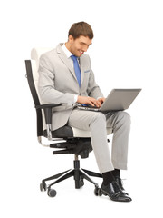 young businessman sitting in chair with laptop
