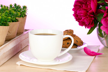 Fototapeta na wymiar filiżankę kawy, ciastka i kwiaty na stole w kawiarni
