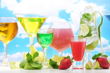 Glasses of cocktails on table on blue sky background