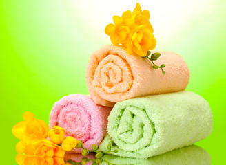 Obraz na płótnie Canvas colorful towels and flowers on green yellow background