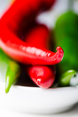 Green and red chili peppers in white bowl