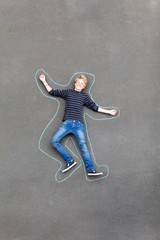 playful teen boy lying on ground with lines drawn around him
