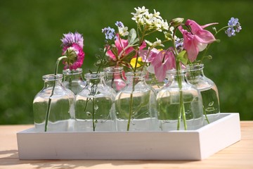 Bunte Gartenblumen in Dekovasen und Holz