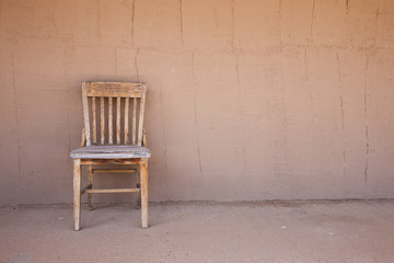 Fototapeta na wymiar Old western chair against an adobe wall