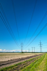 Power line wires and towers, fresh green grass, road and sky