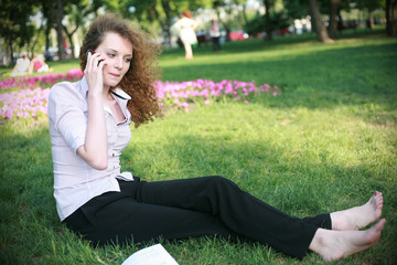 curly-haired girl with the phone sitting on the grass