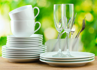 Clean dishes on wooden table on green background