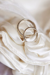wedding rings on white satin fabric