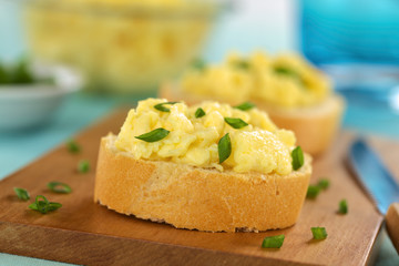 Scrambled eggs on baguette slices with green onion