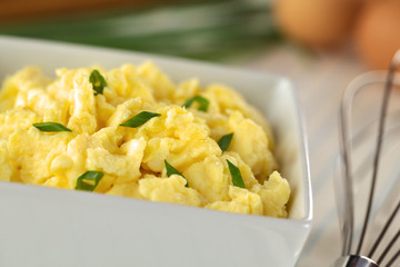 Scrambled eggs with green onion in bowl with beater
