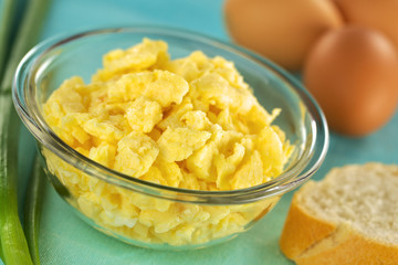 Scrambled eggs in glass bowl with baguette and green onion