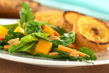 Spinach, mango, carrot salad with peanuts and baguette