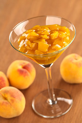 Fresh peach compote in cocktail glass on wood