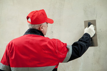 Plasterer in uniform working with float against the wall