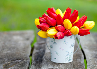 red and yellow tulips in a bucket on garden table