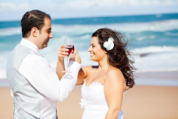 groom and bride drinking  champagne on beach