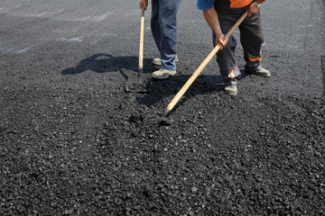 Roadworks, worker with  shovel at asphalt