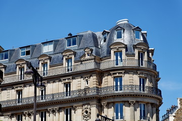 Immeuble de pierre avec toit arrondi et balcons.