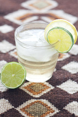 water with lemon and lime in a glass with ice on ethnic mat