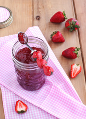 Strawberry jam and fresh strawberries on the wooden table