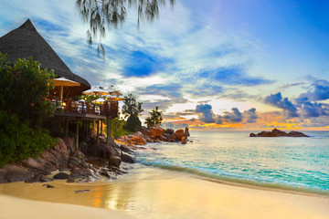 Cafe on tropical beach at sunset - obrazy, fototapety, plakaty