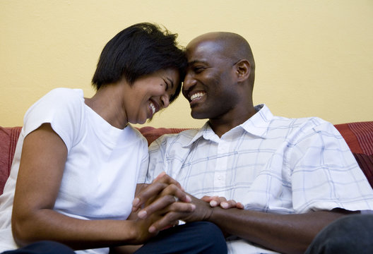 Couple sitting on chouch laughing and cuddling